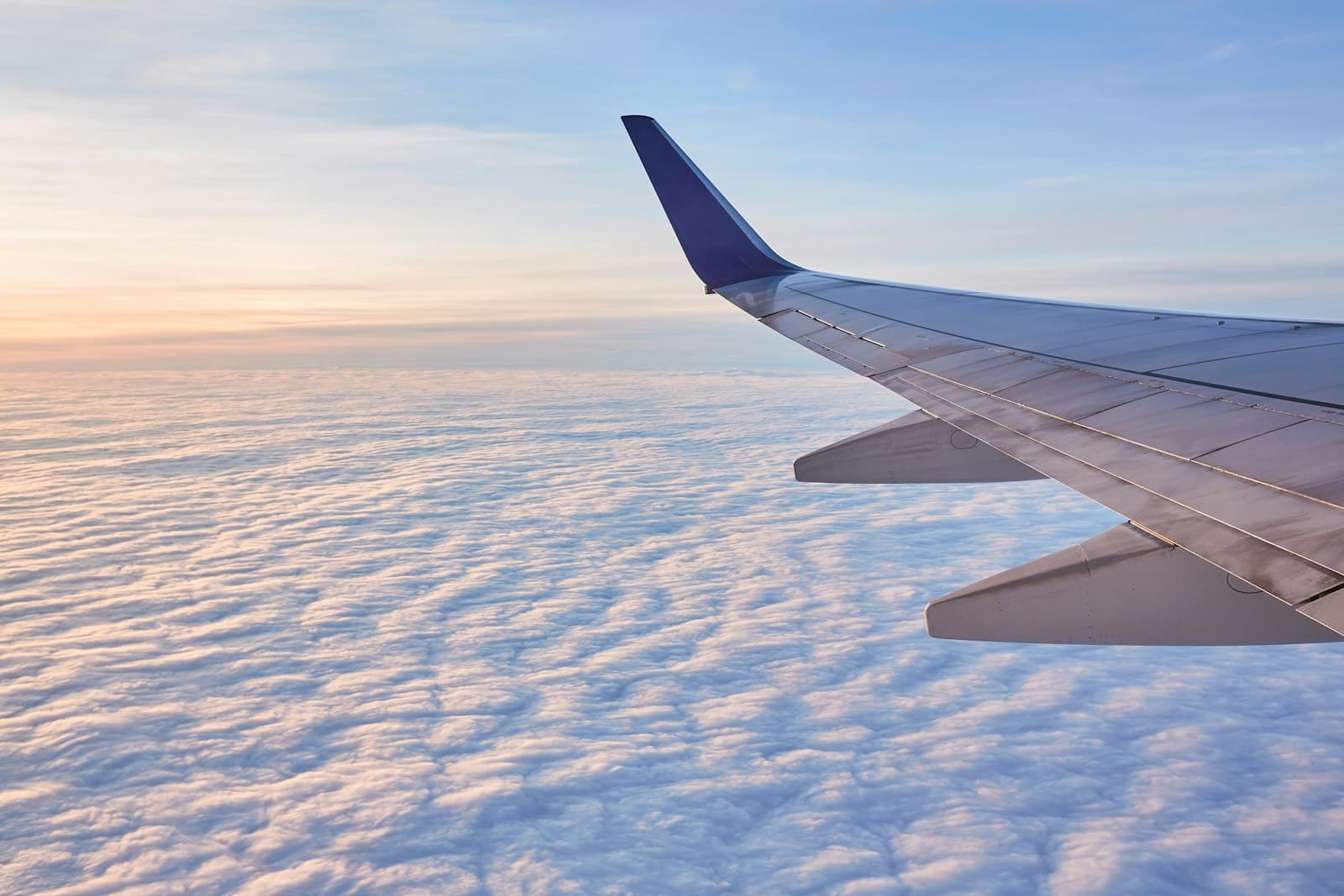 Airplane wing over clouds at sunrise